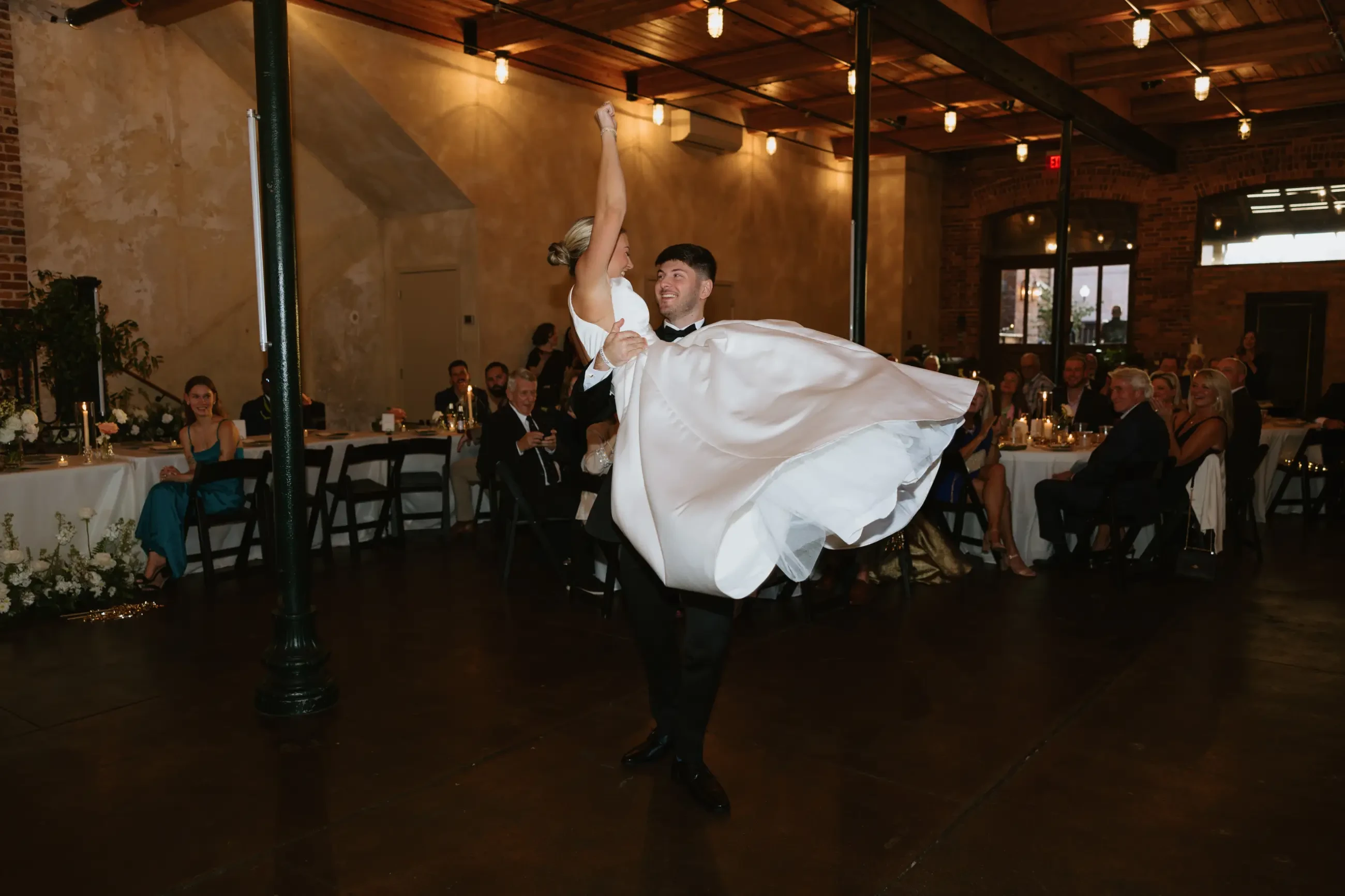 image shows jackson picking up sydney on their wedding day while dancing