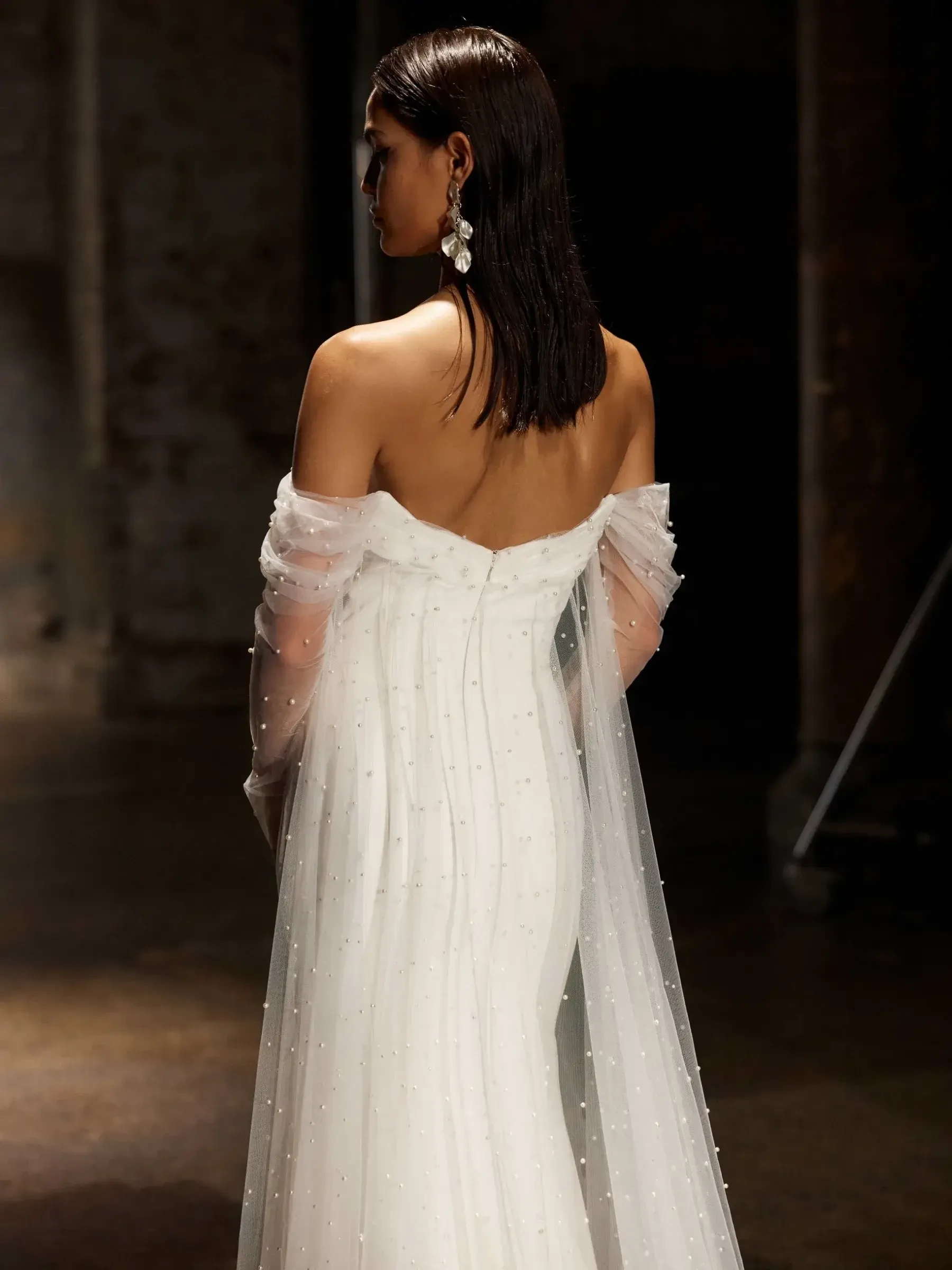 model is wearing an off the shoulder fitted bridal gown by evie young