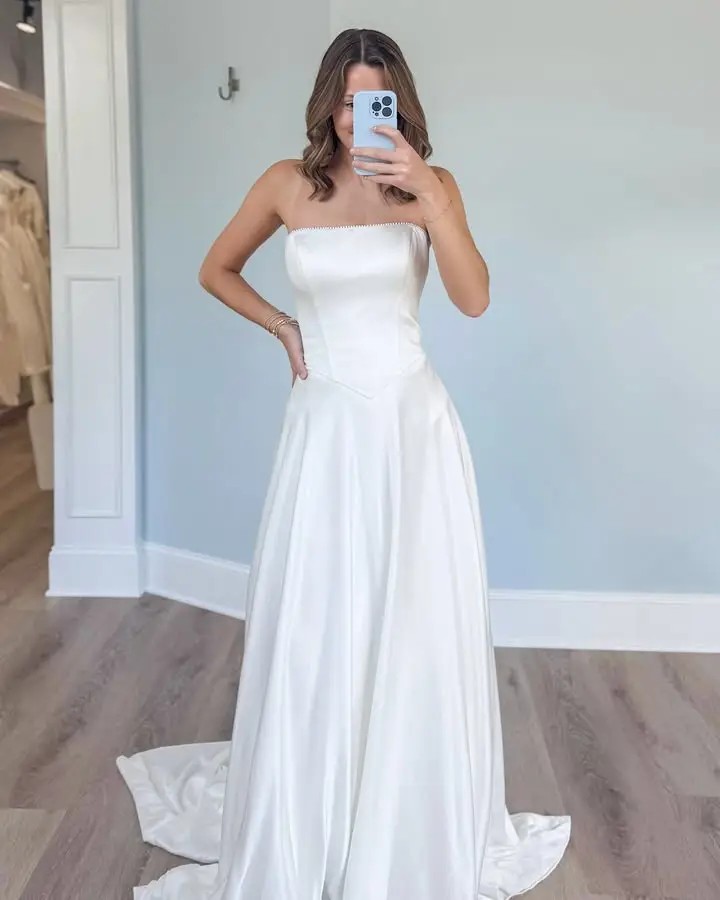 Model is wearing a strapless wedding dress with a basque waist